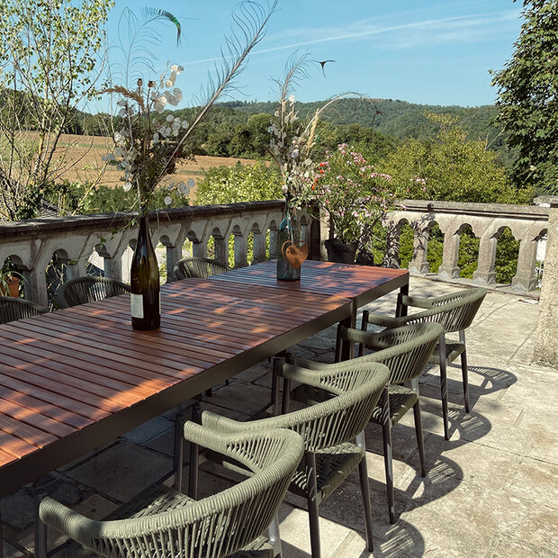 Gartentisch und Sessel auf der Terrasse mit Ausblick ins Grüne